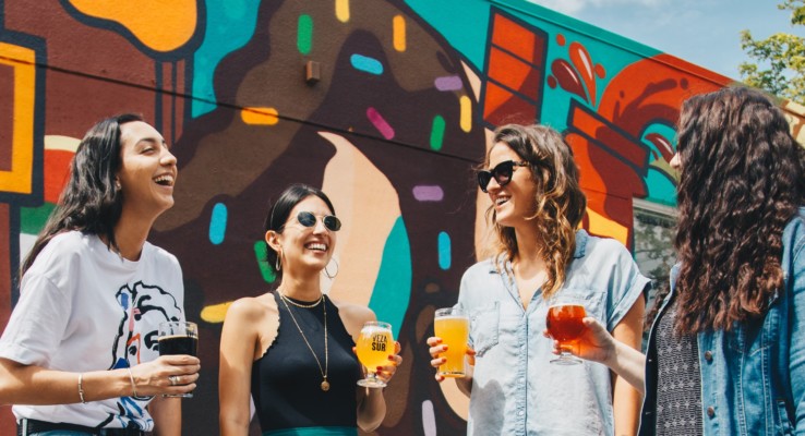 Vier jonge vrouwen drinken een drankje in de zon